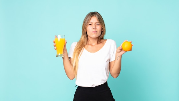 Concetto del succo d'arancia della donna bionda abbastanza giovane?