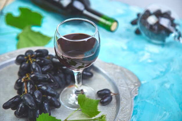 Concetto del vino rosso con la bottiglia, il vetro e l'uva