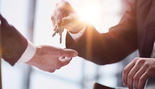 Concetto della giornata mondiale del leasing L'agente immobiliare consegna le chiavi al nuovo proprietario Primo piano delle mani Noleggio e acquisto di beni immobili