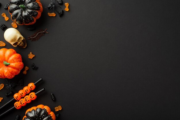 Concetto di accessori per feste di Halloween Foto vista dall'alto di zucche cranio caramelle millepiedi cocktail cannucce e ragni su sfondo nero isolato con copyspace