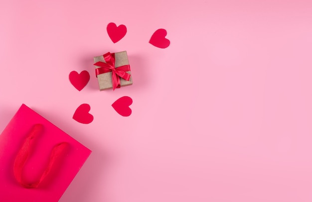 Concetto di acquisto online. Vista dall'alto del sacchetto regalo e dei cuori di carta rosa su sfondo rosa, spazio per la copia, disposizione piatta. Sfondo per San Valentino, compleanno, festa della mamma. Foto di alta qualità