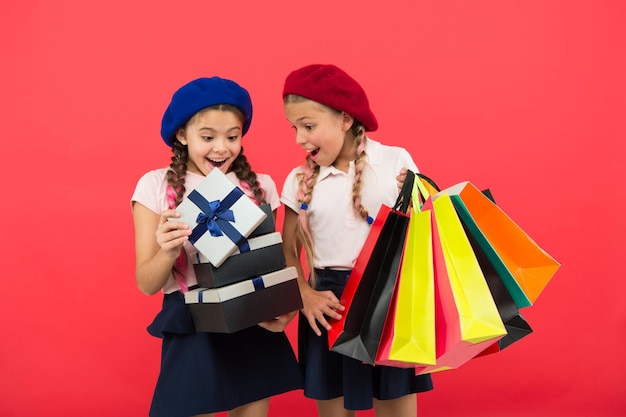 Concetto di acquisto. Piccole ragazze carine per bambini durante lo shopping tour. Miglior prezzo. Acquista ora. Visita il centro commerciale. Le ragazze dei bambini tengono in mano borse della spesa o pacchetti di regali di compleanno. I sogni diventano realtà. Infanzia felice.