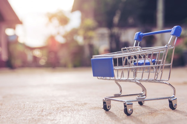 Concetto di acquisto: piccolo giocattolo del carrello vuoto blu sul pavimento di cemento. mercato dello shopping