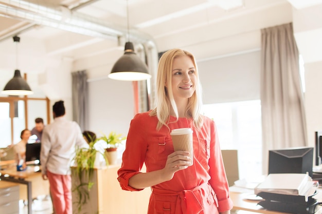 concetto di affari, avvio e persone - donna d'affari felice o impiegato femminile creativo con tazza di caffè