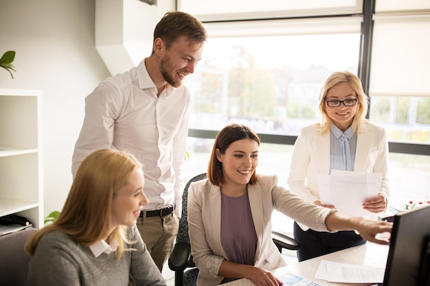 concetto di affari, avvio e persone - felice team creativo in rete con il computer in ufficio