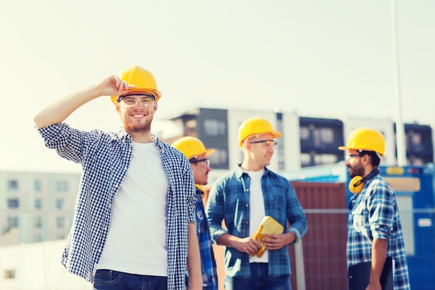 concetto di affari, costruzione, lavoro di squadra e persone - gruppo di costruttori sorridenti in elmetti protettivi all'aperto