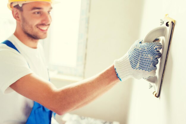 concetto di affari, costruzione, professione e persone - costruttore sorridente con strumento di rettifica all'interno