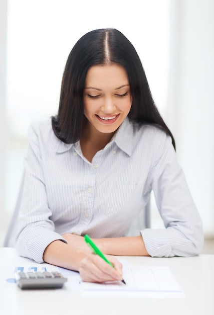 concetto di affari, istruzione e tasse - donna d'affari sorridente o studente che lavora con la calcolatrice