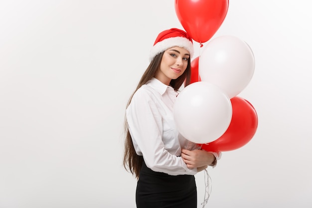 Concetto di affari - La bella giovane donna sicura di affari con il pallone della tenuta del cappello della Santa celebra per Natale.