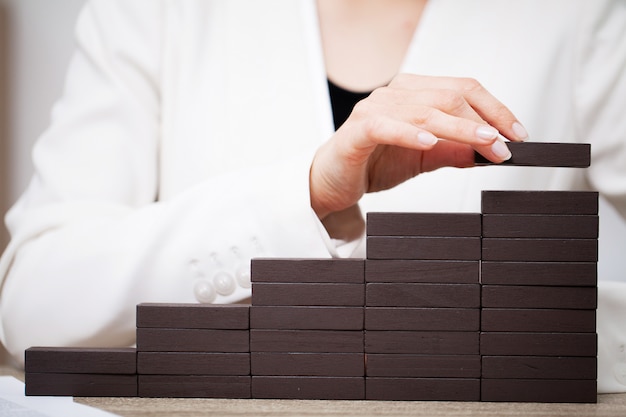 Concetto di affari, le mani della donna compongono cubi di legno che simboleggiano il successo dell'azienda