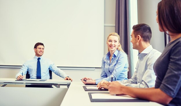 concetto di affari, persone e lavoro di squadra - gruppo di uomini d'affari sorridenti che si incontrano in ufficio