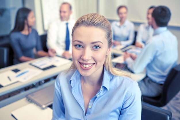 concetto di affari, persone e lavoro di squadra - imprenditrice sorridente con un gruppo di uomini d'affari riuniti in ufficio