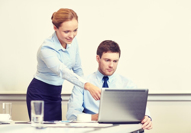 concetto di affari, persone e lavoro - uomo d'affari e segretario con laptop che lavora in ufficio