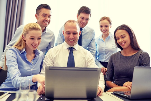 concetto di affari, persone, tecnologia e comunicazione - team di affari sorridente con computer portatile che fa videoconferenza in ufficio