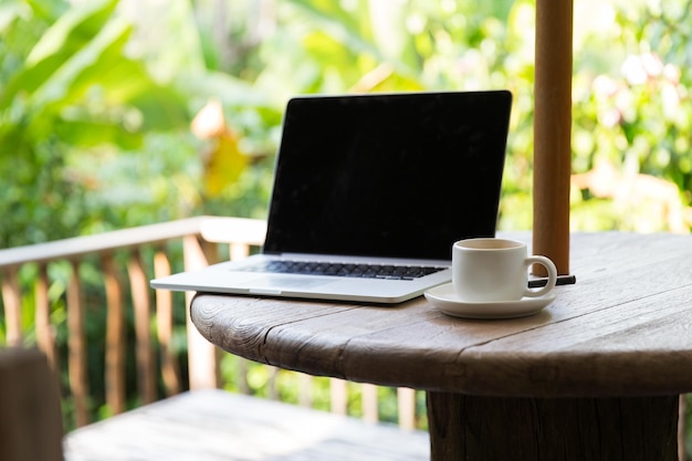 concetto di affari, tecnologia, bevande e oggetti - tazza di caffè e computer portatile sul tavolo all'aperto