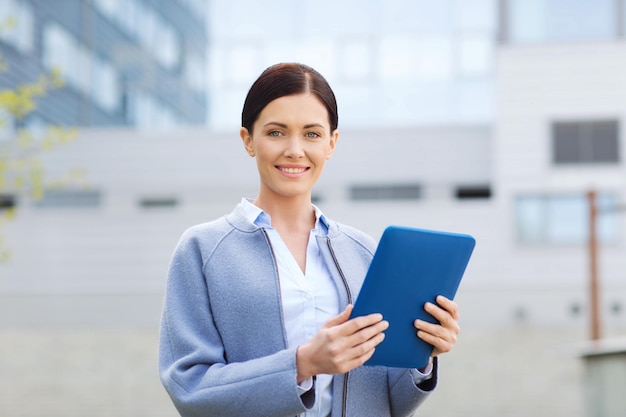 concetto di affari, tecnologia e persone - giovane donna sorridente con computer tablet pc su edificio per uffici