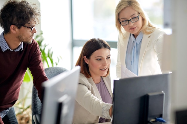 concetto di affari, tecnologia, lavoro di squadra e persone: felice team creativo con il computer in ufficio