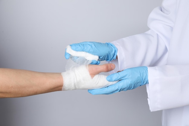 Concetto di aiuto durante un infortunio medico che avvolge la mano nella benda su sfondo bianco
