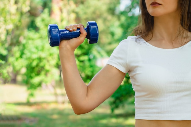 Concetto di allenamento sportivo La mano femminile sta tenendo un dumbbell blu