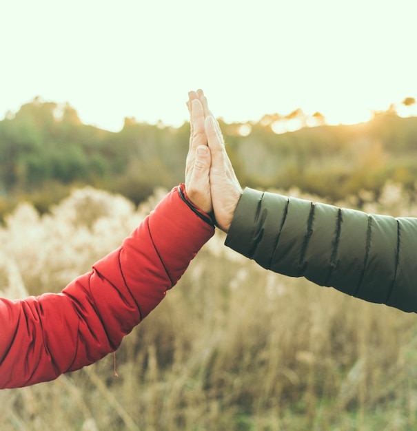 Concetto di amicizia e relazione con le mani strette uomo e donna all'aperto con la natura sullo sfondo persone irriconoscibili Squadra e aiuto coppia Dare cinque Amore e amici attività ricreativa