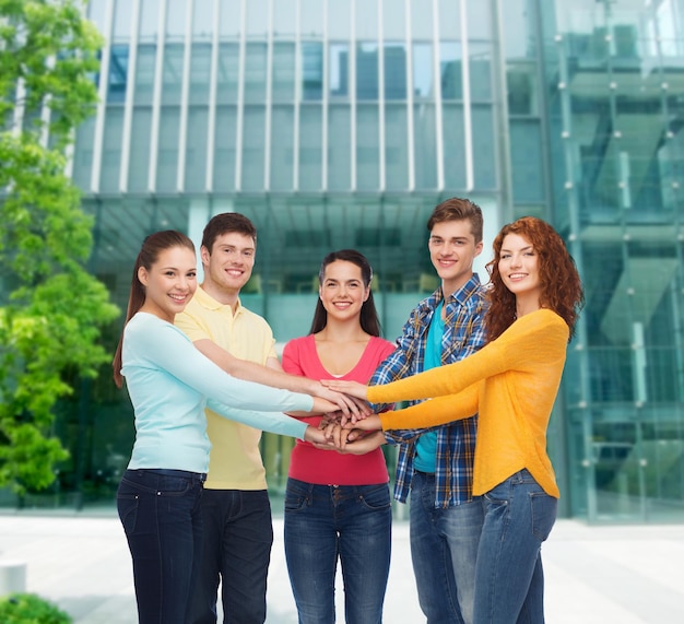 concetto di amicizia, educazione, affari, gesto e persone - gruppo di adolescenti sorridenti con le mani una sopra l'altra sullo sfondo del campus