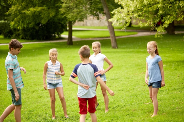 concetto di amicizia, infanzia, tempo libero e persone - gruppo di bambini felici o amici che giocano nel parco estivo