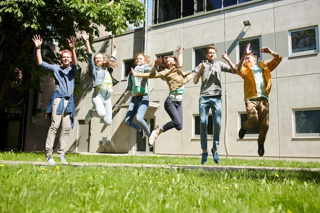 concetto di amicizia, movimento, azione, libertà e persone - gruppo di studenti o amici adolescenti felici che saltano all'aperto