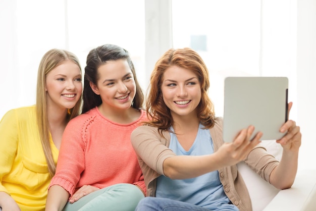 concetto di amicizia, tecnologia e internet - tre ragazze adolescenti sorridenti che scattano foto con la fotocamera del computer tablet pc a casa