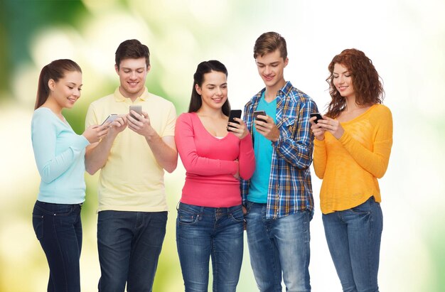 concetto di amicizia, tecnologia, ecologia e persone - gruppo di adolescenti sorridenti con smartphone su sfondo naturale