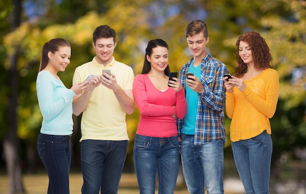 concetto di amicizia, tecnologia, natura e persone - gruppo di adolescenti sorridenti con smartphone sullo sfondo del parco