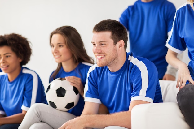 concetto di amicizia, tempo libero, sport e intrattenimento: amici felici o tifosi di calcio con la palla che guardano il calcio a casa