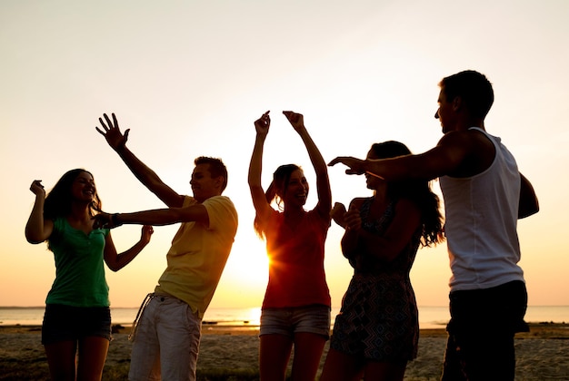 concetto di amicizia, vacanze estive, vacanze, feste e persone - gruppo di amici sorridenti che ballano sulla spiaggia