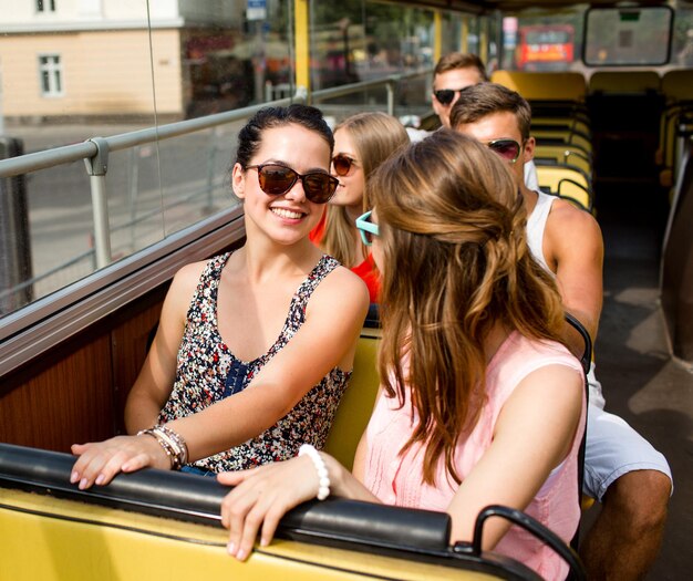 concetto di amicizia, viaggi, vacanze, estate e persone - gruppo di amici sorridenti che viaggiano in autobus turistico