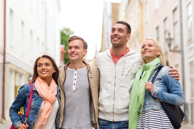 concetto di amicizia, viaggio e vacanza - gruppo di amici sorridenti che camminano in città