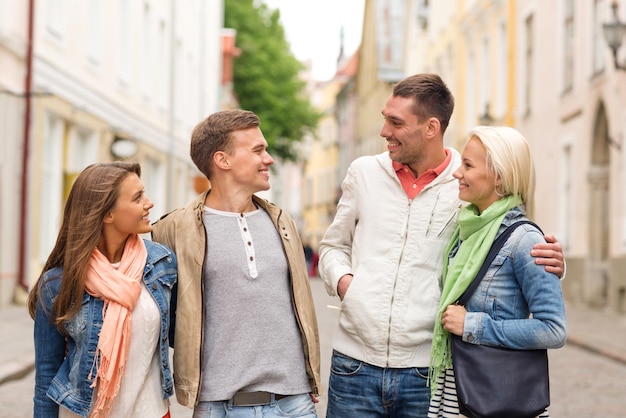 concetto di amicizia, viaggio e vacanza - gruppo di amici sorridenti che camminano in città