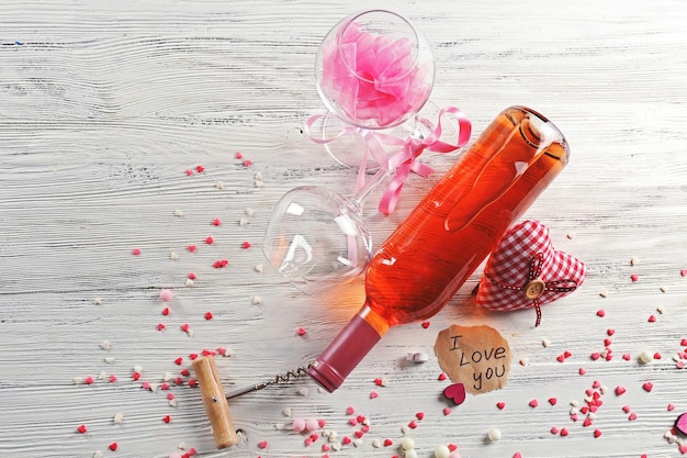 Concetto di amore - bottiglia di vino con decorazioni su fondo di legno bianco, primi piani