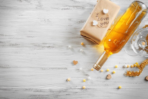 Concetto di amore - bottiglia di vino con decorazioni su fondo di legno bianco