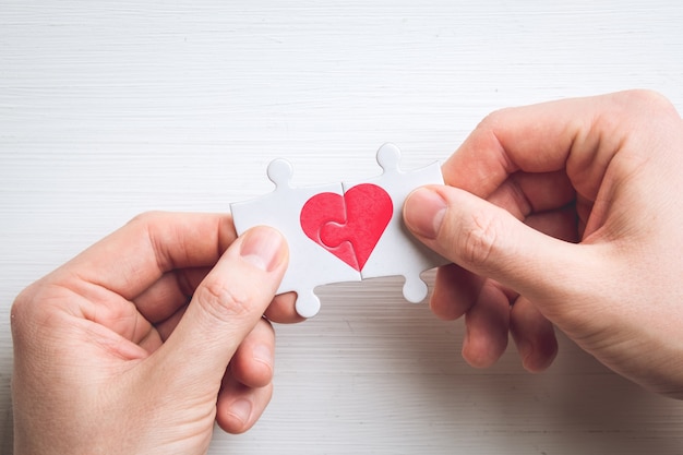 Concetto di amore da due puzzle con un cuore in mano.