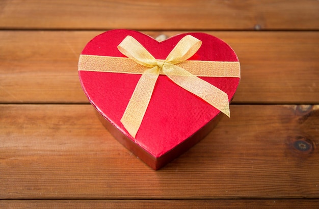 concetto di amore, data, romanticismo, giorno di san valentino e vacanze - primo piano della confezione regalo a forma di cuore su legno