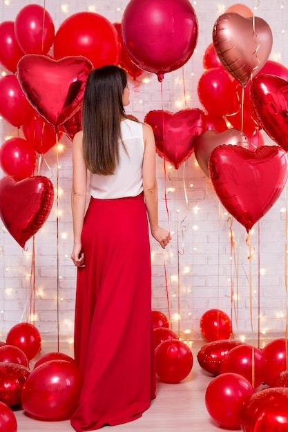 Concetto di amore e san valentino - vista posteriore di una donna snella con palloncini a forma di cuore