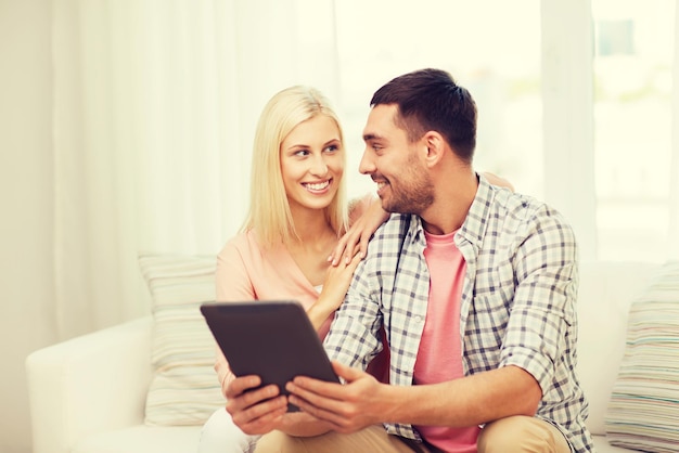 concetto di amore, famiglia, tecnologia, internet e felicità - coppia felice sorridente con computer tablet pc a casa