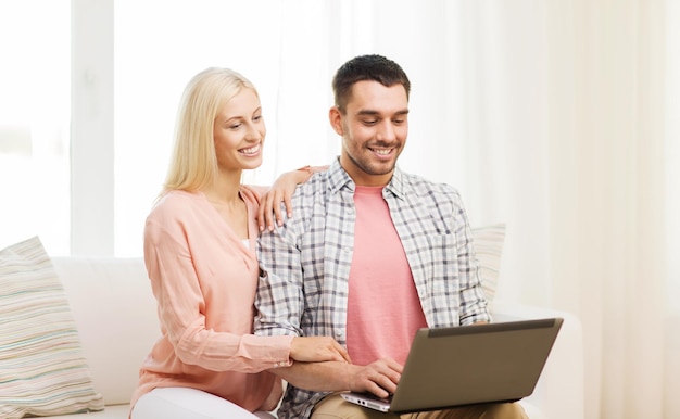 concetto di amore, famiglia, tecnologia, internet e felicità - coppia felice sorridente con un computer portatile a casa