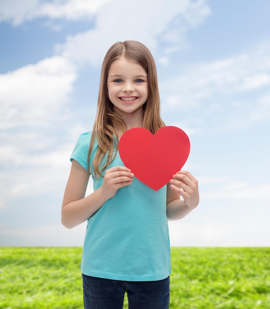 concetto di amore, felicità e persone - bambina sorridente con cuore rosso