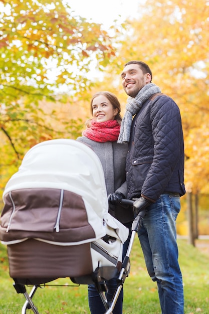 concetto di amore, genitorialità, famiglia, stagione e persone - coppia sorridente con carrozzina nel parco autunnale