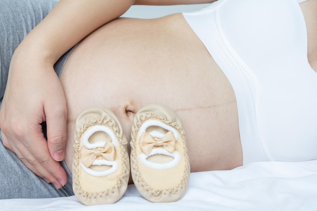 Concetto di amore per la gravidanza Giovane incinta e le sue scarpe per bambini