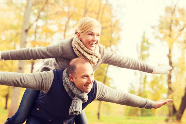 concetto di amore, relazione, famiglia e persone - coppia sorridente che si diverte nel parco autunnale