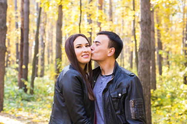 Concetto di amore, relazione, famiglia e persone - uomo che bacia sua moglie nel parco autunnale.