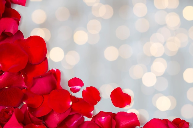 concetto di amore, romanticismo, giorno di san valentino e vacanze - primo piano di petali di rose rosse con copyspace su sfondo di luci