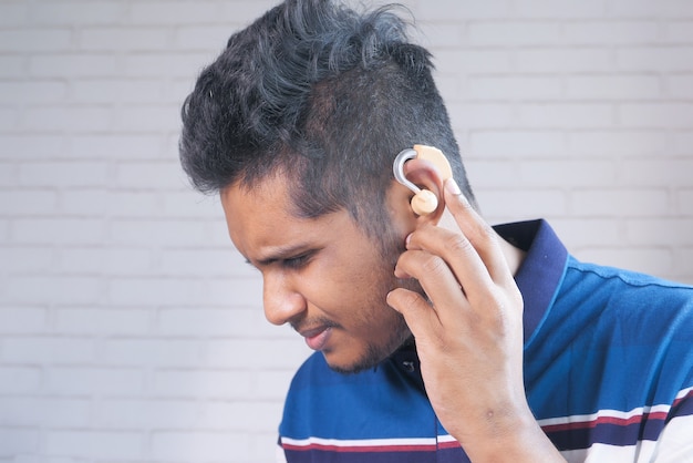 Concetto di apparecchio acustico, un giovane con problemi di udito.