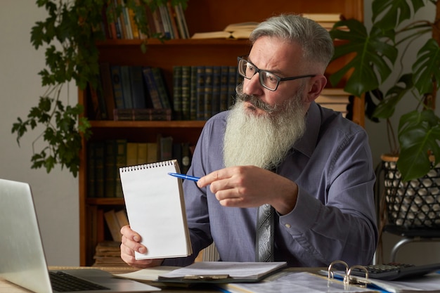 Concetto di apprendimento a distanza. Insegnante, traduttore, tutor sul desktop della biblioteca indica con la penna sul piatto bianco